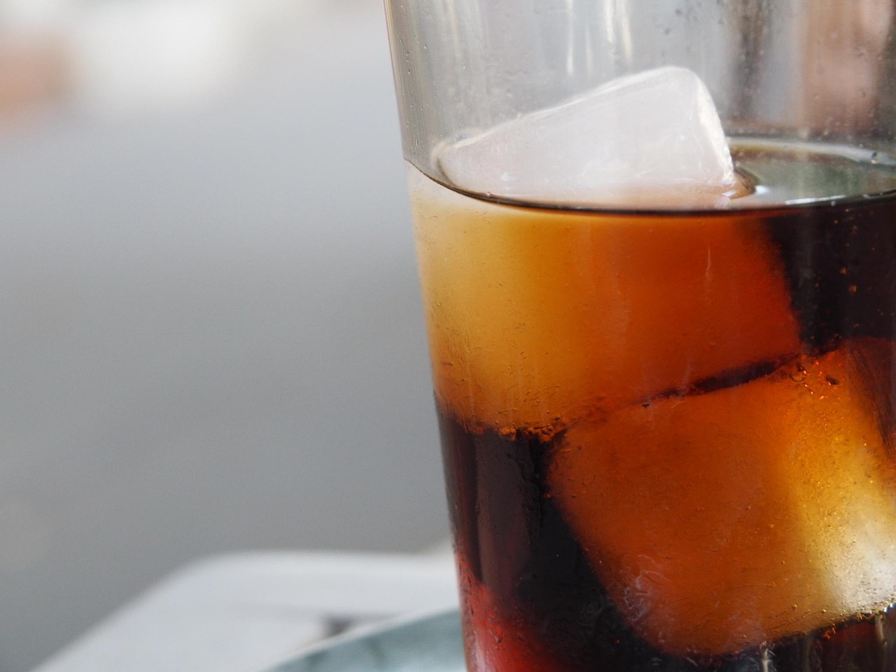 Tazza di caffè cold brew su un tavolo, circondata da ghiaccio e chicchi di caffè.