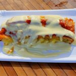 Crema pasticcera liscia coperta da pellicola trasparente mentre raffredda in una ciotola.